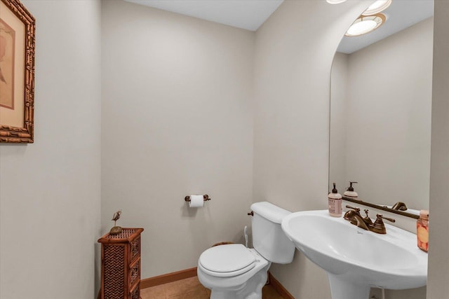 bathroom featuring tile patterned flooring, toilet, baseboards, and a sink