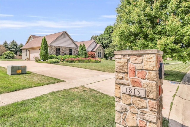 ranch-style home with a front lawn, concrete driveway, stone siding, and an attached garage