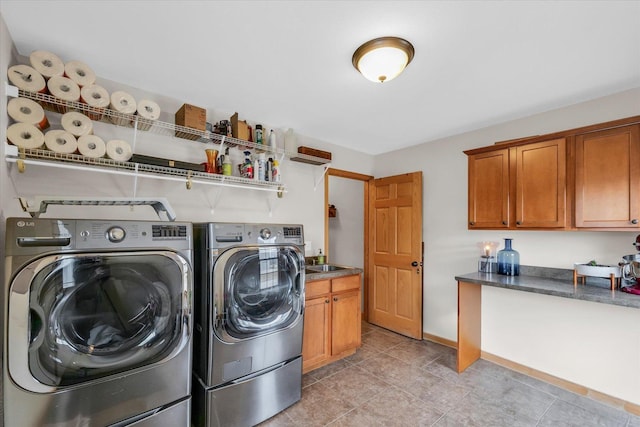 washroom featuring washer and dryer, baseboards, cabinet space, and a sink