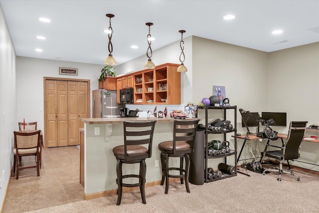 kitchen featuring brown cabinets, a kitchen breakfast bar, freestanding refrigerator, recessed lighting, and a peninsula