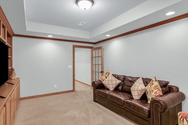 living area featuring baseboards, visible vents, light carpet, crown molding, and a raised ceiling