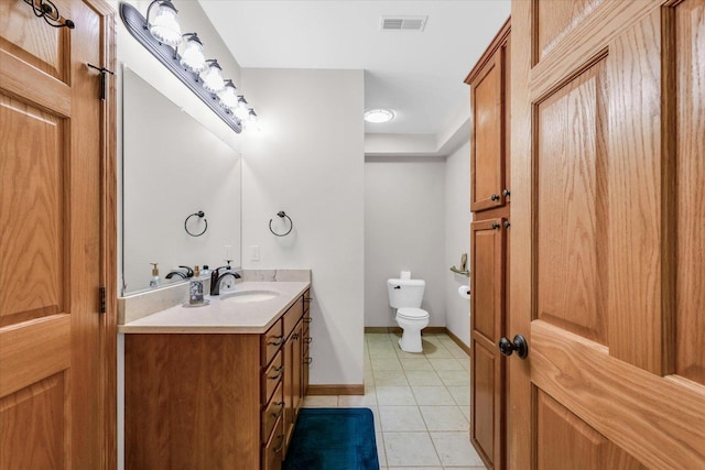 bathroom with vanity, baseboards, visible vents, tile patterned floors, and toilet