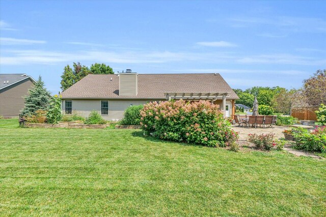 back of house with a patio, a yard, a pergola, and a chimney