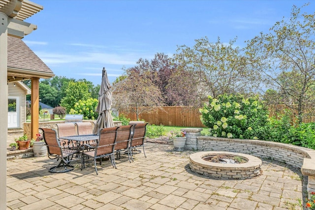 view of patio with outdoor dining area, an outdoor fire pit, and fence