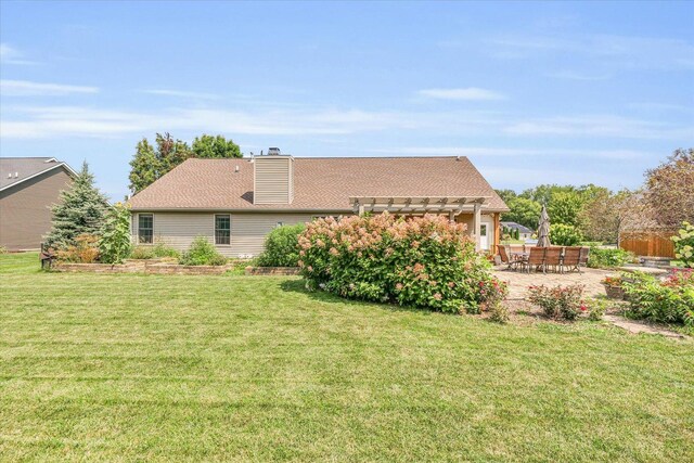 back of house with a lawn, a pergola, a chimney, and a patio area