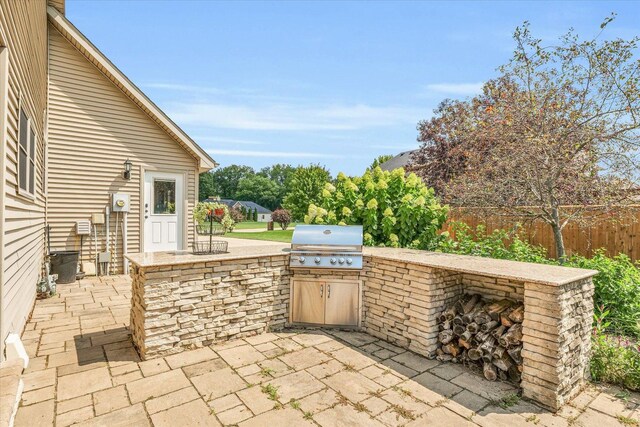 view of patio with grilling area, an outdoor kitchen, and fence