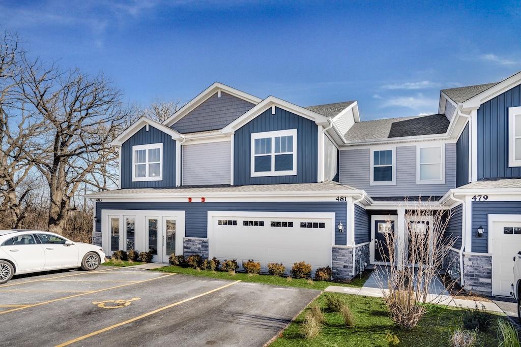 1127 White Oak Cir, Crystal Lake, IL 60012 - view of front facade featuring stone siding, board and batten siding, roof with shingles, and uncovered parking