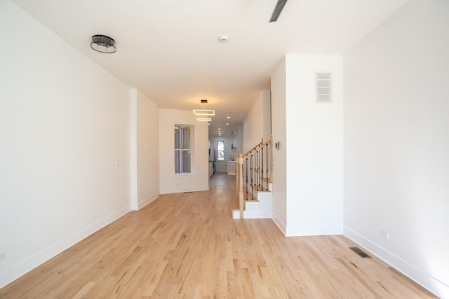 hallway with visible vents, stairway, light wood-style floors, and baseboards