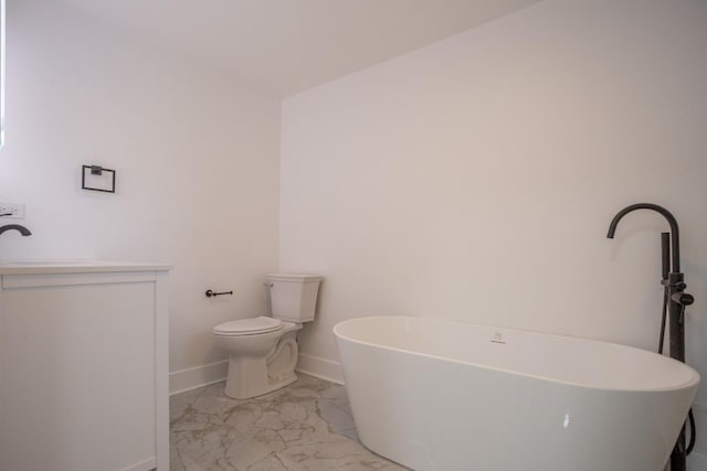 full bath with baseboards, toilet, a freestanding tub, marble finish floor, and a sink