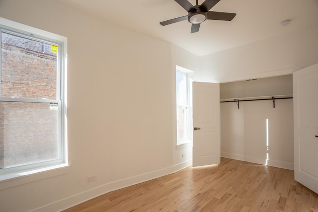 unfurnished bedroom featuring multiple windows, baseboards, and light wood-type flooring
