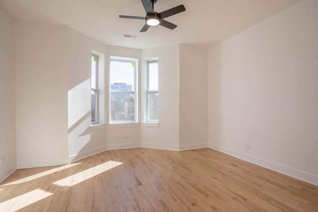 unfurnished room featuring ceiling fan, wood finished floors, visible vents, and baseboards
