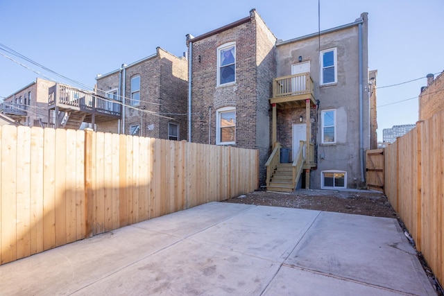 rear view of property featuring a patio, a balcony, a fenced backyard, and brick siding