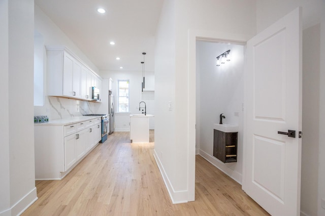 kitchen featuring white cabinets, appliances with stainless steel finishes, light countertops, and light wood-type flooring