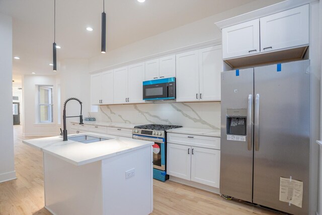 kitchen featuring light wood-style flooring, a sink, white cabinetry, stainless steel appliances, and decorative backsplash