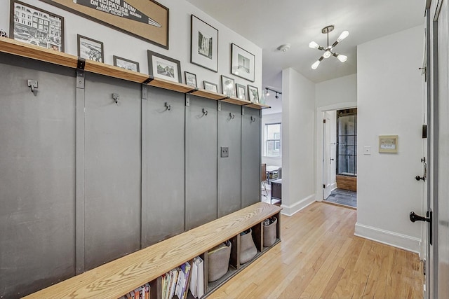 mudroom featuring a notable chandelier, light wood-type flooring, and baseboards