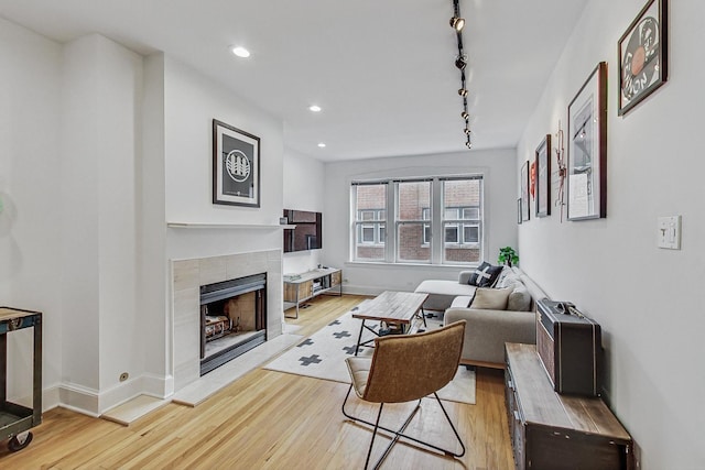 living area featuring recessed lighting, baseboards, a tile fireplace, and light wood finished floors