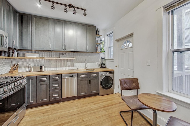 kitchen with wooden counters, open shelves, appliances with stainless steel finishes, washer / clothes dryer, and a sink