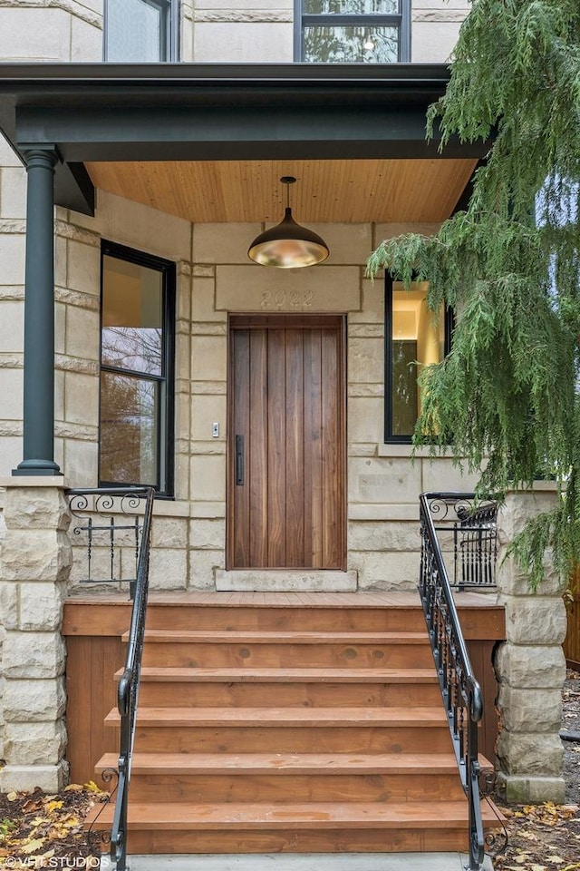 entrance to property featuring stone siding and a porch