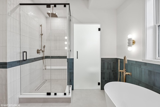 bathroom with a wainscoted wall, a stall shower, tile walls, tile patterned flooring, and a soaking tub