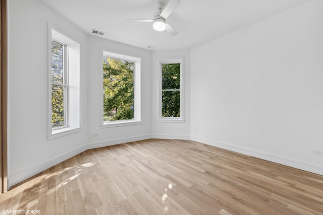 empty room featuring visible vents, ceiling fan, light wood-type flooring, and baseboards