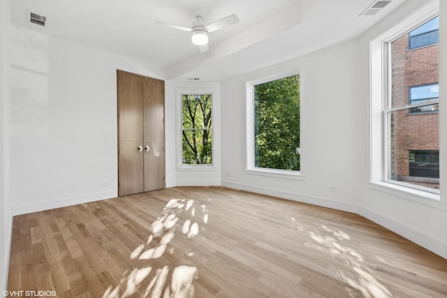 unfurnished room with light wood-style floors, visible vents, and baseboards