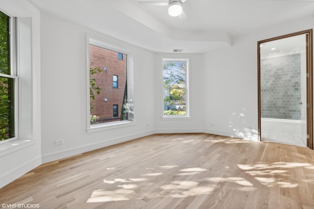 unfurnished room with a ceiling fan, visible vents, wood finished floors, and baseboards