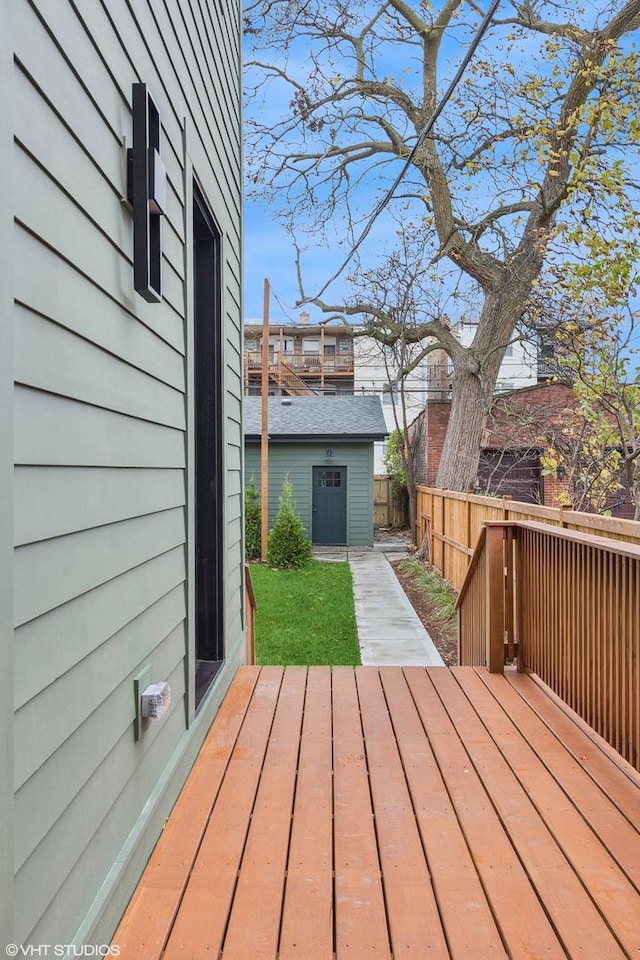 wooden terrace with an outdoor structure and a fenced backyard