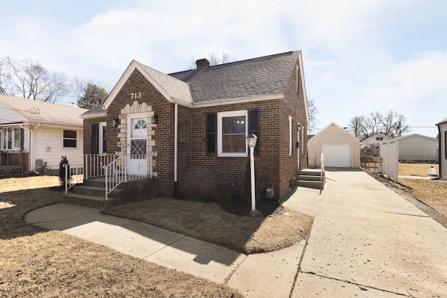 view of front of property featuring brick siding, a shingled roof, a detached garage, an outdoor structure, and driveway