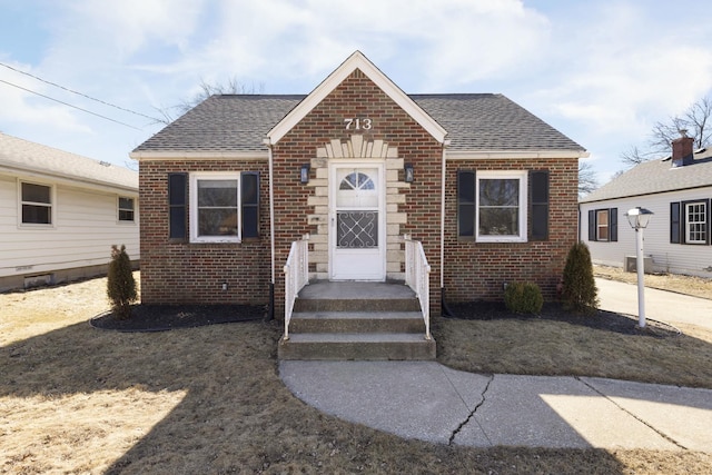 view of front facade featuring brick siding and roof with shingles