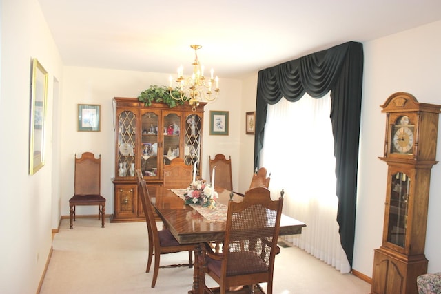 dining space featuring baseboards, light carpet, and an inviting chandelier