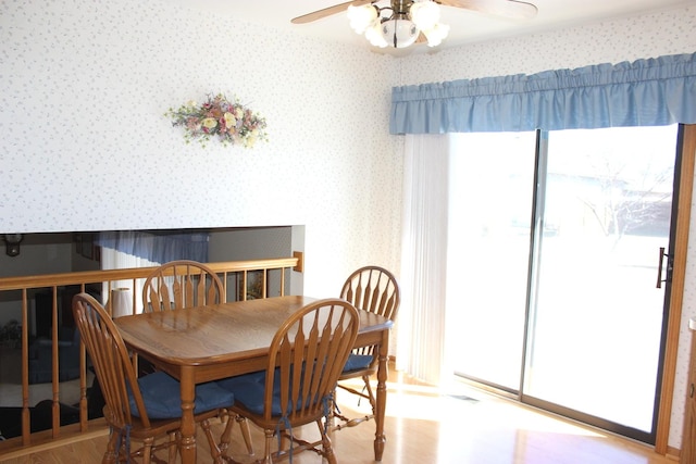 dining room with wallpapered walls, plenty of natural light, wood finished floors, and ceiling fan