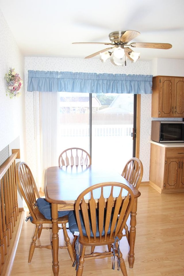 dining space with light wood finished floors, wallpapered walls, and ceiling fan