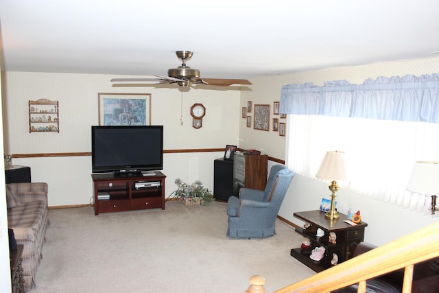 carpeted living area with wallpapered walls, a ceiling fan, and baseboards