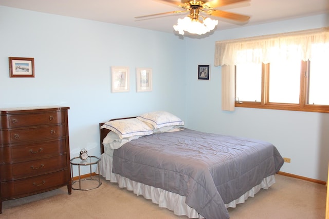 bedroom featuring light colored carpet, baseboards, and ceiling fan