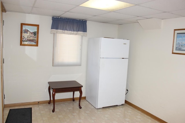 kitchen with a drop ceiling, baseboards, light floors, and freestanding refrigerator