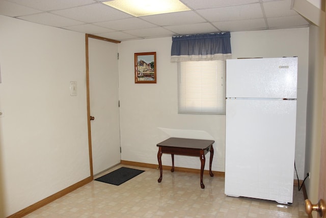 interior space featuring tile patterned floors, baseboards, and a paneled ceiling