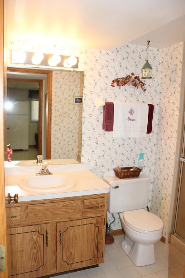 bathroom featuring toilet, a shower with door, wallpapered walls, tile patterned flooring, and vanity