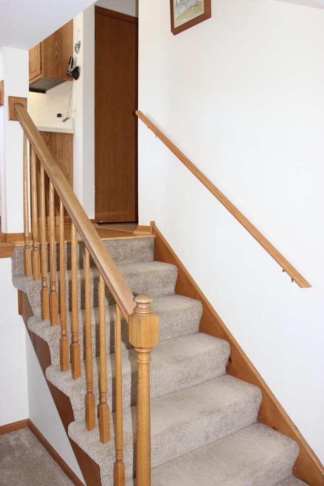 staircase with baseboards and carpet flooring