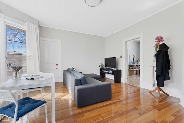 living room featuring light wood finished floors, baseboards, and ornamental molding