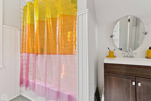 bathroom featuring vanity, a shower, and a wainscoted wall