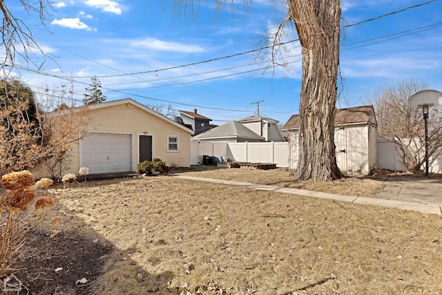 view of yard featuring a garage, an outbuilding, and fence