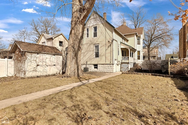 view of side of property with a storage unit, fence, cooling unit, an outdoor structure, and a chimney