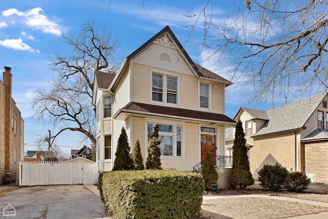 victorian-style house with a shingled roof and a gate