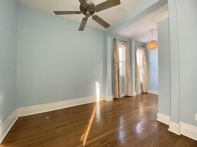 spare room with dark wood-style floors, a textured ceiling, a ceiling fan, and baseboards