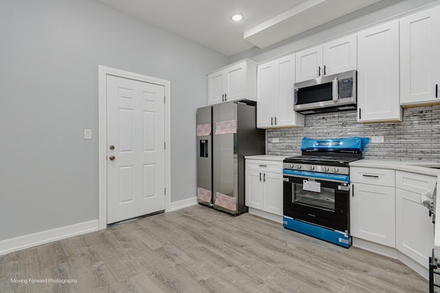 kitchen with light wood-type flooring, stainless steel appliances, white cabinets, light countertops, and decorative backsplash