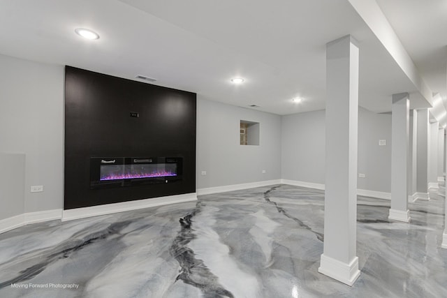 finished below grade area featuring a glass covered fireplace, recessed lighting, visible vents, and baseboards