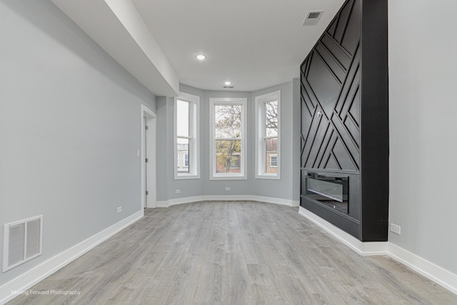 unfurnished living room featuring visible vents, baseboards, and light wood-style flooring