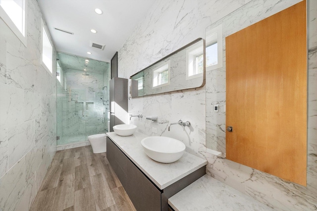 bathroom featuring toilet, visible vents, a marble finish shower, and a sink