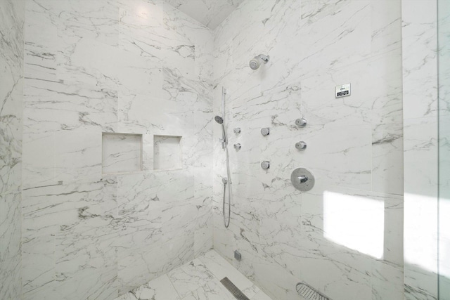 bathroom with stone wall, marble finish floor, and a marble finish shower