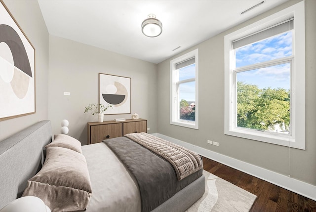 bedroom featuring baseboards, multiple windows, visible vents, and dark wood-style flooring